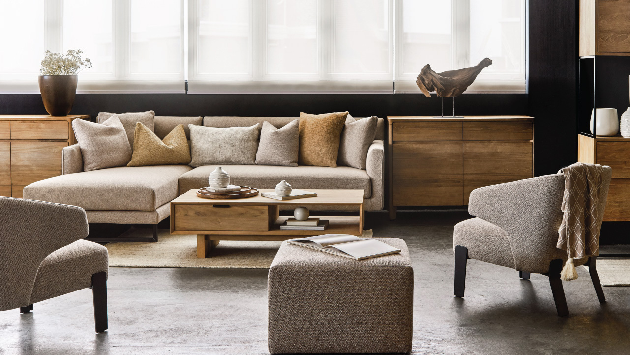 客廳裡的角位梳化、木茶几、布藝腳凳,以及兩張灰褐色扶手椅,後方是木製餐邊櫃